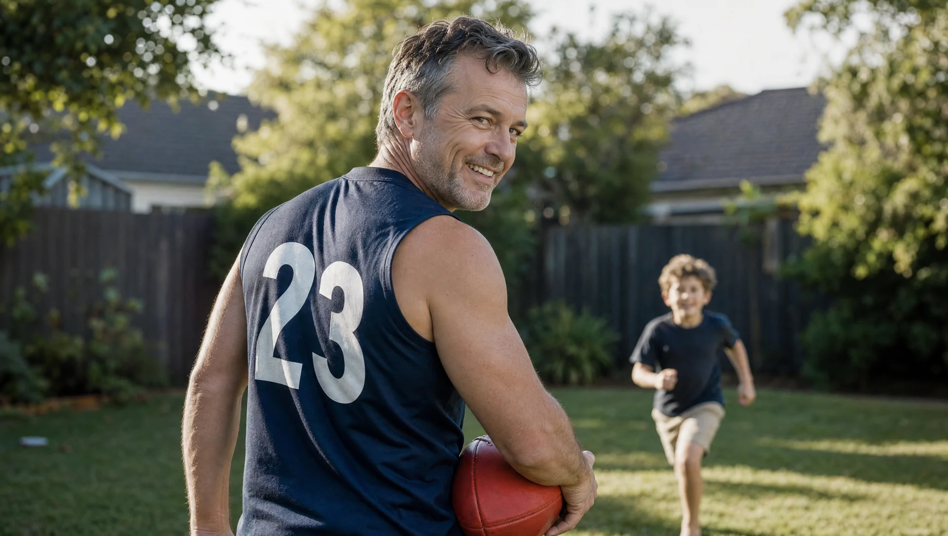 A father holding a football while playing with his child in the backyard